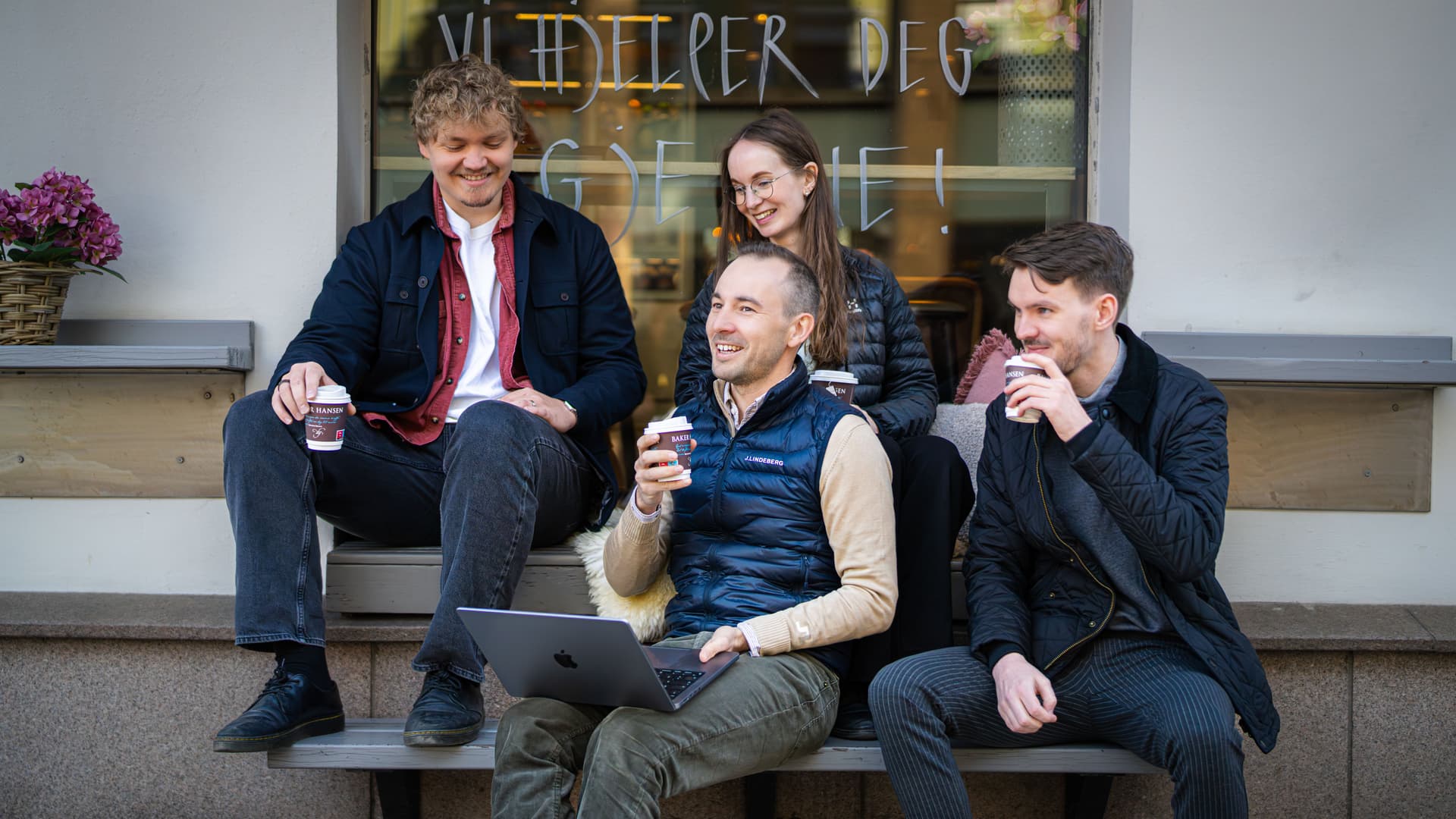Bredvid-konsulenter sitter utendørs og drikker kaffe sammen.